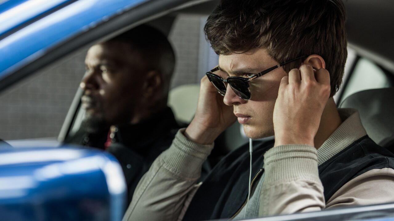 Baby (ANSEL ELGORT) and Bats (JAMIE FOXX) on the way to the post office job with Buddy (JON HAMM) and Darling (EIZA GONZALEZ) as cops pull up next to them in TriStar Pictures' BABY DRIVER.